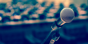 A graphic of a microphone with crowd of people in background