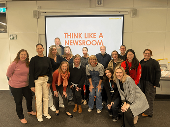 Group of Knox City Council staff in front of a screen displaying 'Think Like a Newsroom