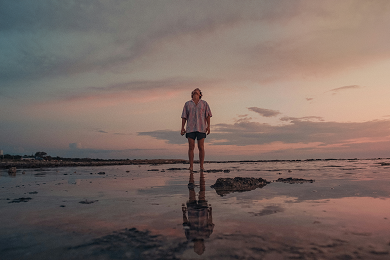 Man on beach at sunrise looking into the sky