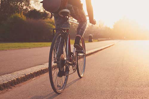 Rear-view of person riding a bicycle into the sunset