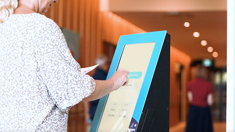 Woman using large touch-screen information kiosk